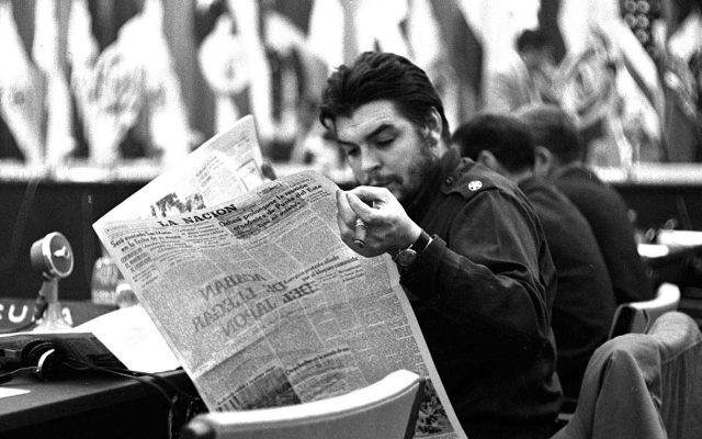 Che Guevara membaca akhbar La Nación / Che Guevara reading La Nación at a conference table, 1961.
