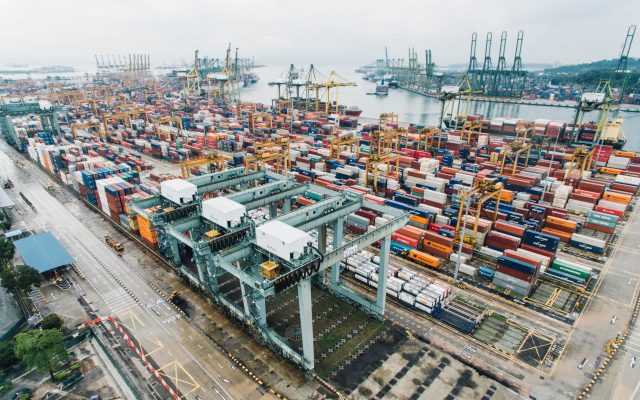 Aerial view of cranes and stacked shipping containers at a Singapore container terminal.